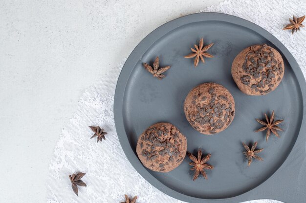 Um prato escuro com biscoitos de chocolate com anis estrelado.