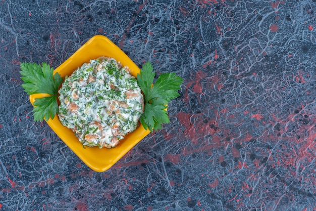 Foto grátis um prato fundo amarelo com uma deliciosa salada e ervas.