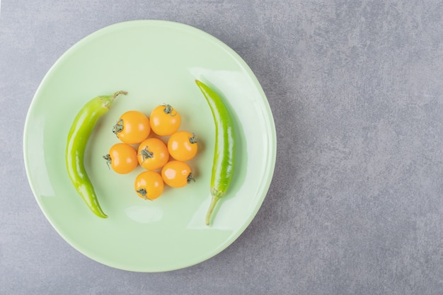 Um prato verde com tomate cereja e pimenta malagueta