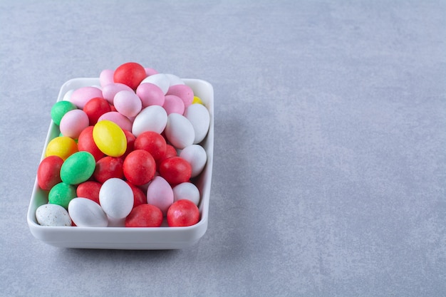 Foto grátis um quadro branco cheio de doces de feijão coloridos na superfície cinza