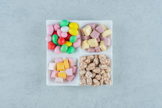 Um quadro branco com marshmallows e doces coloridos na superfície branca
