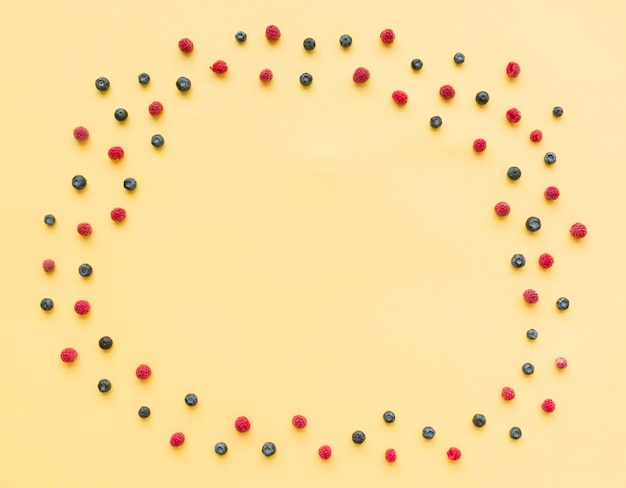 Um quadro circular vazio feito com mirtilos e framboesas em fundo bege