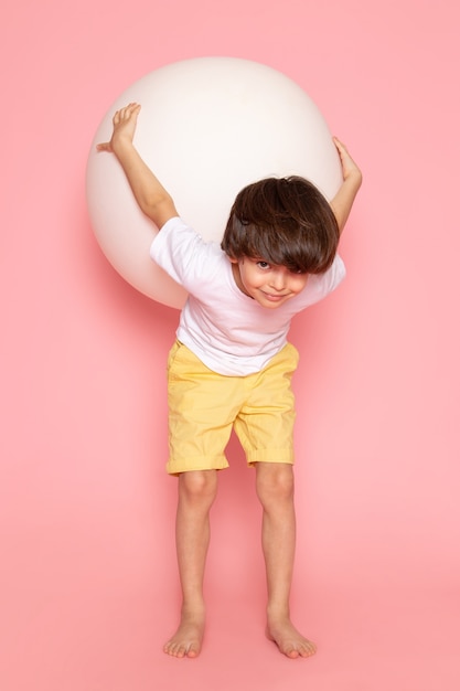 Um rapaz bonito vista frontal em camiseta branca, jogando com bola branca redonda na mesa-de-rosa