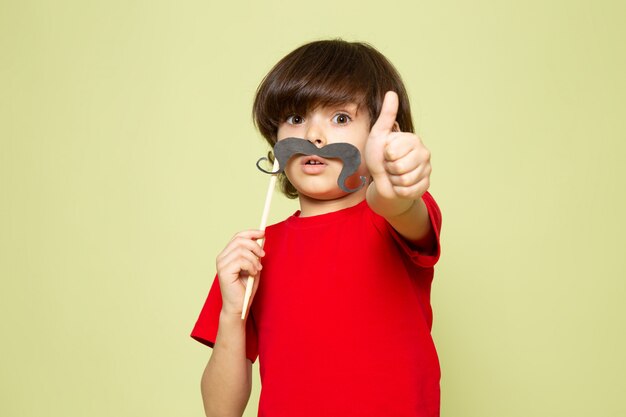 Um rapaz bonito vista frontal em t-shirt vermelha segurando o bigode no espaço colorido de pedra