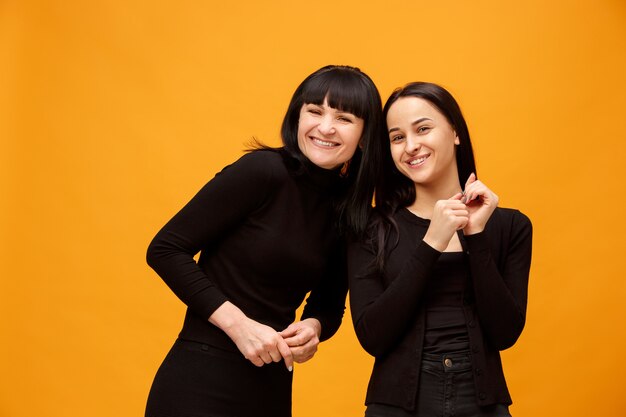 Um retrato de uma mãe e filha felizes e sorridentes no estúdio em ouro