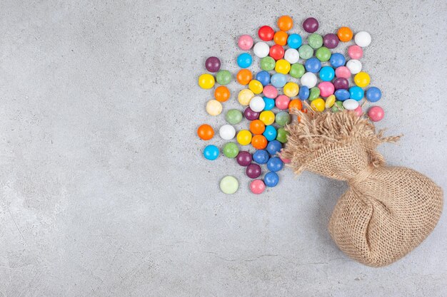 Um saco com um monte de doces espalhados ao lado no fundo de mármore. Foto de alta qualidade