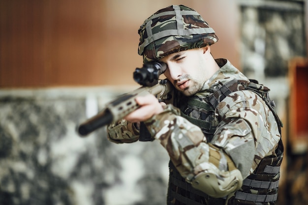 Um soldado militar mira e segura um rifle grande no prédio