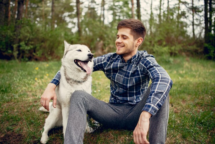 Foto grátis um tipo bonito num parque de verão com um cão.