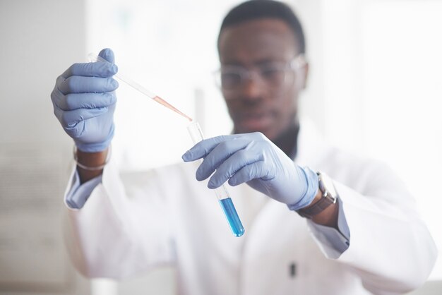 Um trabalhador afro-americano trabalha em um laboratório conduzindo experimentos.