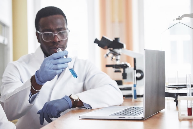 Um trabalhador afro-americano trabalha em um laboratório conduzindo experimentos.