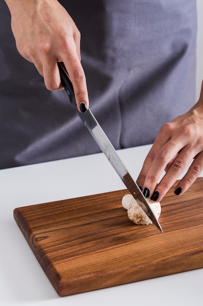 Um, visão aérea, de, um, mulher jovem, corte, a, faca, com, cogumelo, ligado, madeira, tábua chopping