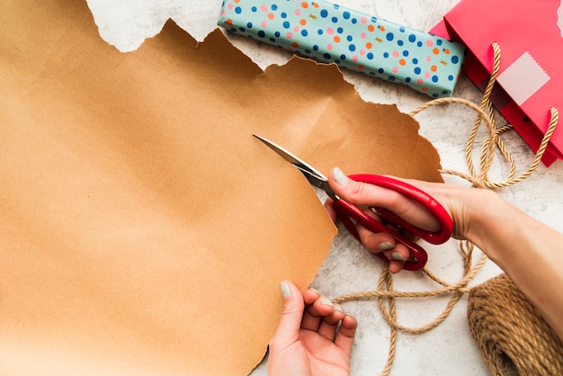 Foto grátis um, visão aérea, de, um, pessoa, mão, corte, a, papel marrom, com, scissor