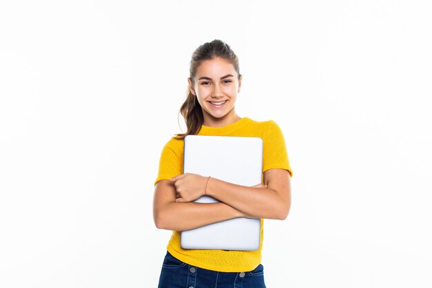 Uma adolescente bonita a sorrir a usar um portátil sobre uma parede branca.