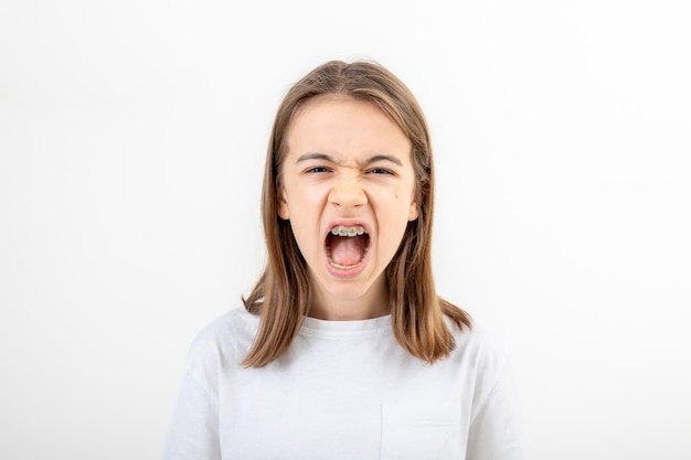 Uma adolescente com aparelhos ortopédicos grita com a boca aberta