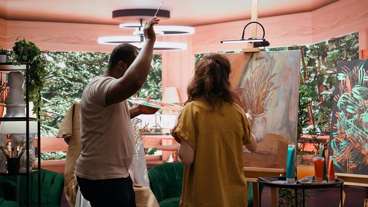 Foto grátis uma artista alegre e seu aprendiz aplicando aquarela em tela
