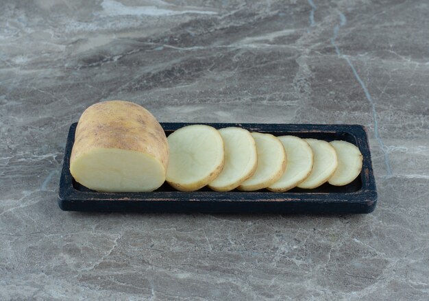 Uma bandeja com fatias de batata, sobre a mesa de mármore.