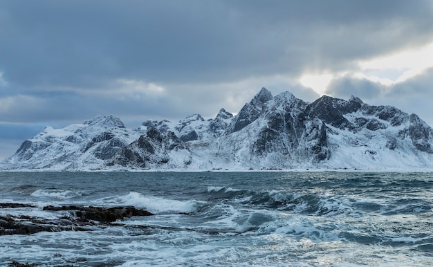 Uma bela foto das ondas do mar com uma montanha de neve ao fundo