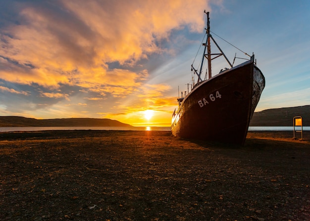 Uma bela foto de um barco de pesca se aproximando da praia ao nascer do sol