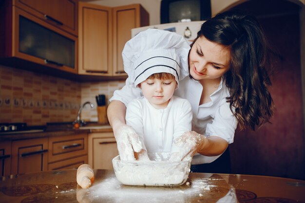 Uma bela jovem mãe com sua filha está cozinhando na cozinha em casa