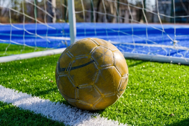 Foto grátis uma bola de futebol deitada no campo esportivo verde entre os portões