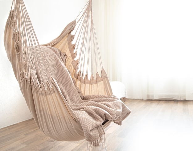 Foto grátis uma cadeira com rede está pendurada no quarto. lugar aconchegante para relaxar em casa.