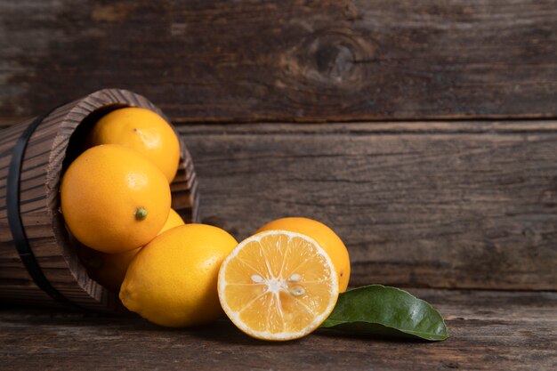 Uma cesta de madeira cheia de frutas frescas de limão com folhas colocadas sobre uma mesa de madeira. Foto de alta qualidade