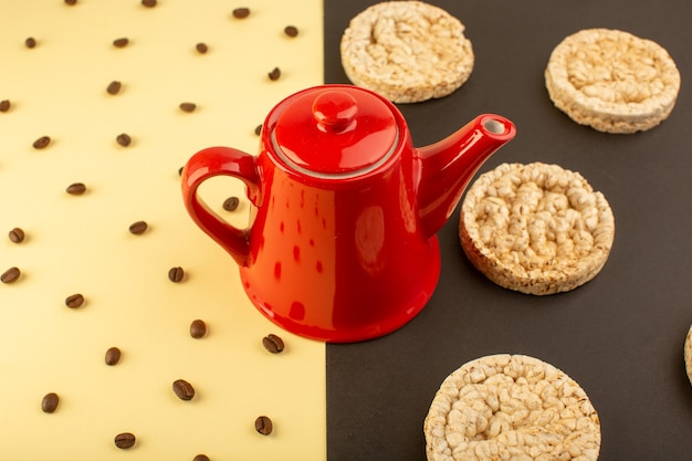 Uma chaleira vermelha de vista superior com sementes de café marrom e biscoitos