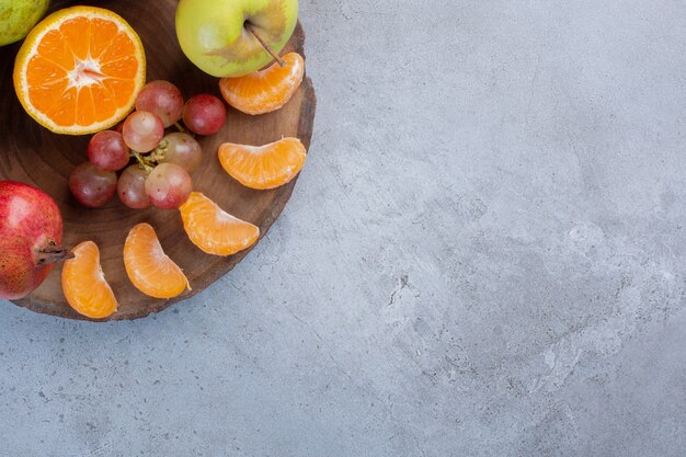 Uma deliciosa porção de frutas em uma placa de madeira com fundo de mármore.