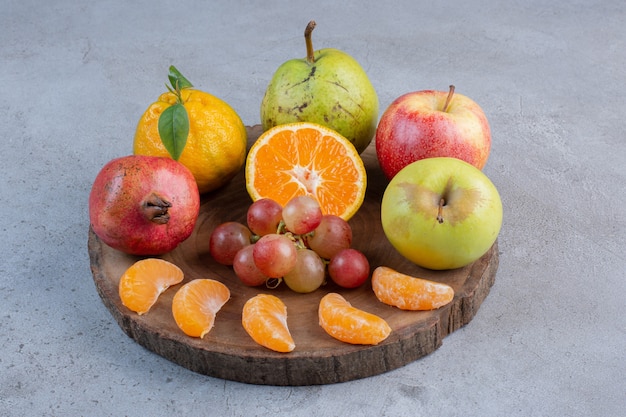 Uma deliciosa porção de frutas em uma placa de madeira com fundo de mármore.