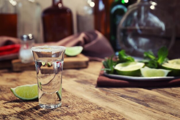 Uma dose de tequila com limão suculento e sal na mesa de madeira
