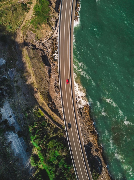 Uma estrada estreita e curvilínea com carros ao lado de montanhas verdes