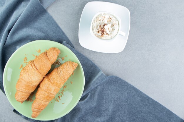 Uma exibição de croissant no prato na toalha e com café, no fundo de mármore. Foto de alta qualidade