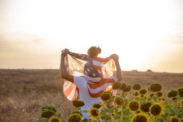 Uma família feliz com uma bandeira americana ao pôr do sol.