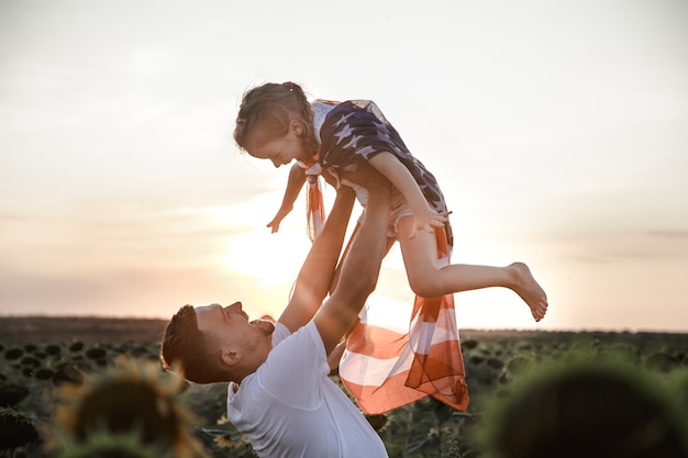 Uma família feliz com uma bandeira americana ao pôr do sol.