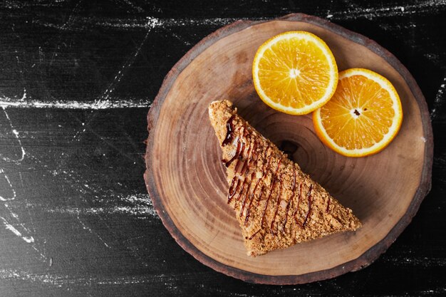 Uma fatia de bolo de mel com rodelas de laranja.