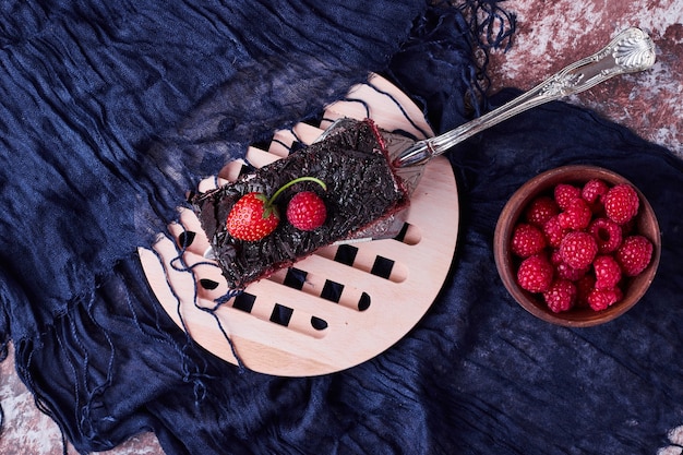 Uma fatia de cheesecake de chocolate com frutas vermelhas.