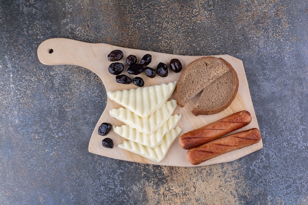 Uma fatia de pão servida com linguiça e queijo em uma tábua de madeira Foto gratuita