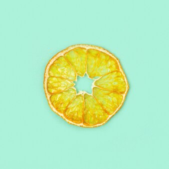 Uma fatia de tangerina de frutas secas sobre fundo de cor de menta. batatas fritas desidratadas. alimentos dietéticos. lanche saudável ou doces. conceito de dieta à base de plantas. Foto Premium
