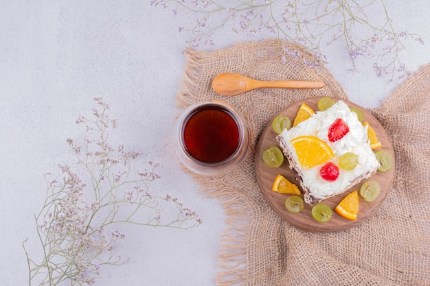 Uma fatia quadrada de bolo de frutas com um copo de chá.