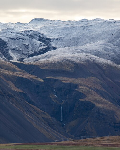 Uma foto vertical de montanhas com neve no topo