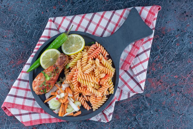 Uma frigideira de macarrão espiral e carne de coxa de frango.