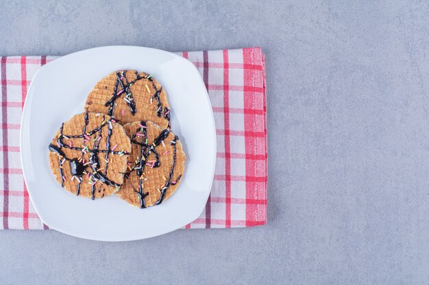 Uma frigideira de waffle vermelho redondo com granulado e creme.