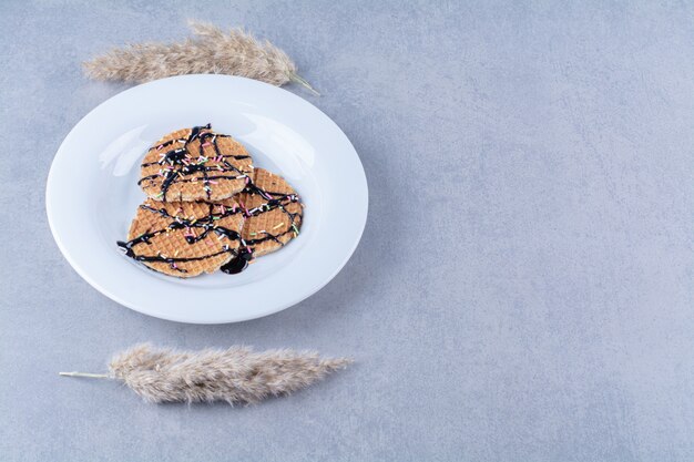 Uma frigideira de waffle vermelho redondo com granulado e creme.