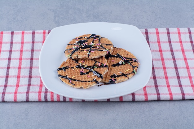 Uma frigideira de waffle vermelho redondo com granulado e creme