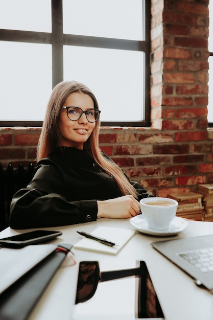 Uma funcionária de sucesso no escritório com uma xícara de café