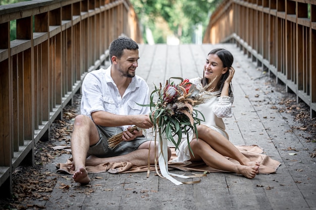 Uma garota e um jovem sentam-se na ponte e apreciam a comunicação, um encontro na natureza, uma história de amor.