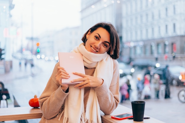 Uma garota em um café aconchegante se aquece com uma xícara de café quente