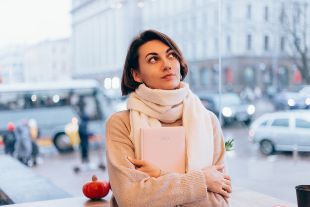 Uma garota em um café aconchegante se aquece com uma xícara de café quente