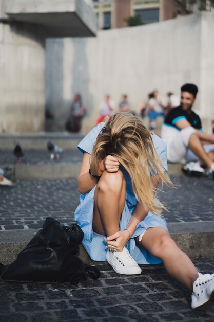 Uma garota está sentada na Praça Dam. Amesterdão