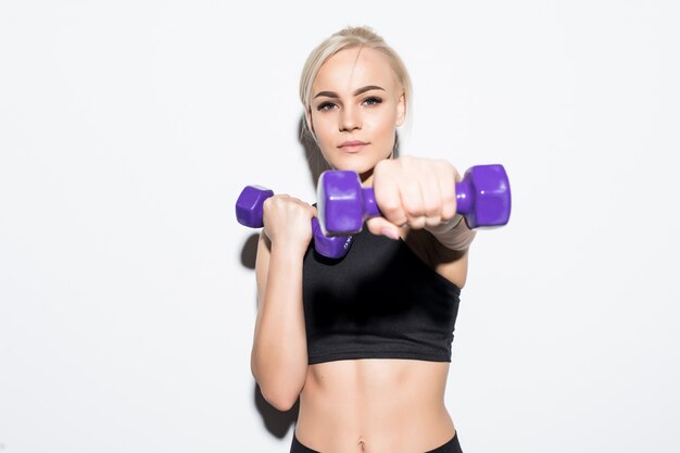 Uma garota loira musculosa e forte com halteres azuis em branco